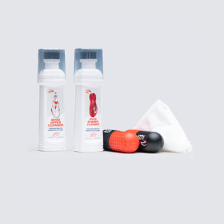 azza sports Two bottles of shoe rubber cleaner, a black and red cleaning tool, and a white cloth on a light gray background.